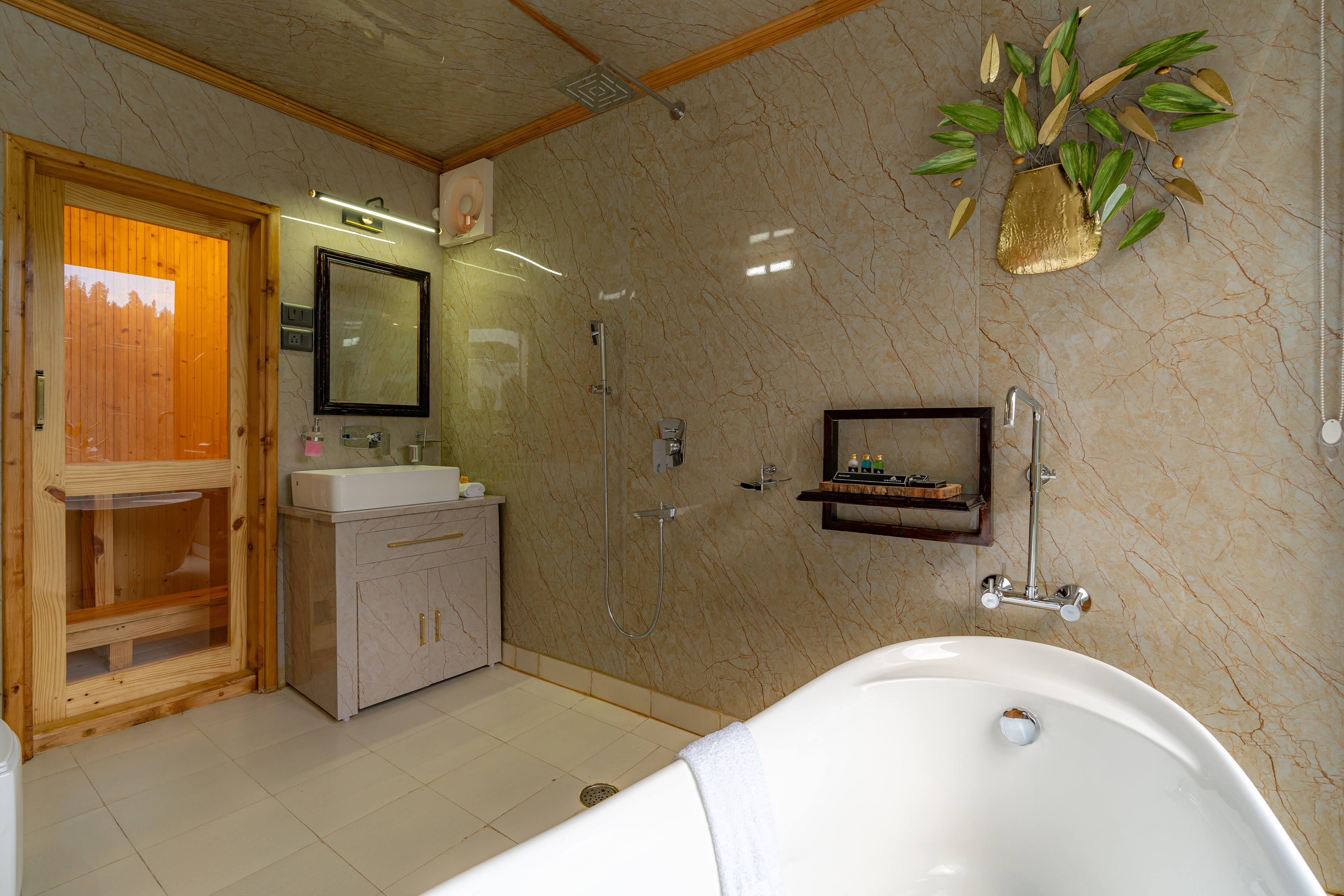 Marble bathroom with freestanding tub and a warm wooden sauna cabin glowing beside it