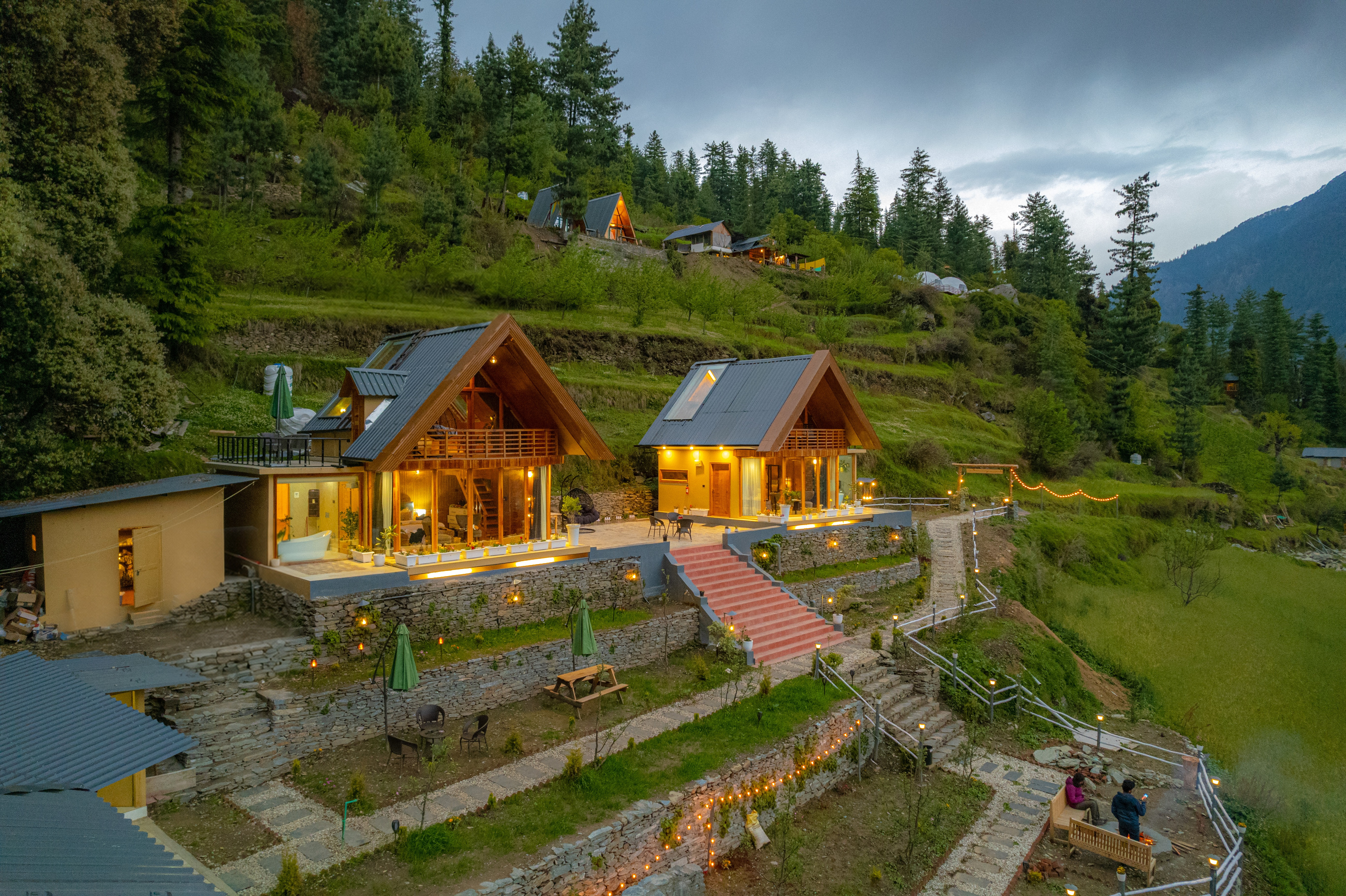 The Mandukya villas glowing at dusk on a terraced hillside above the Banjar valley