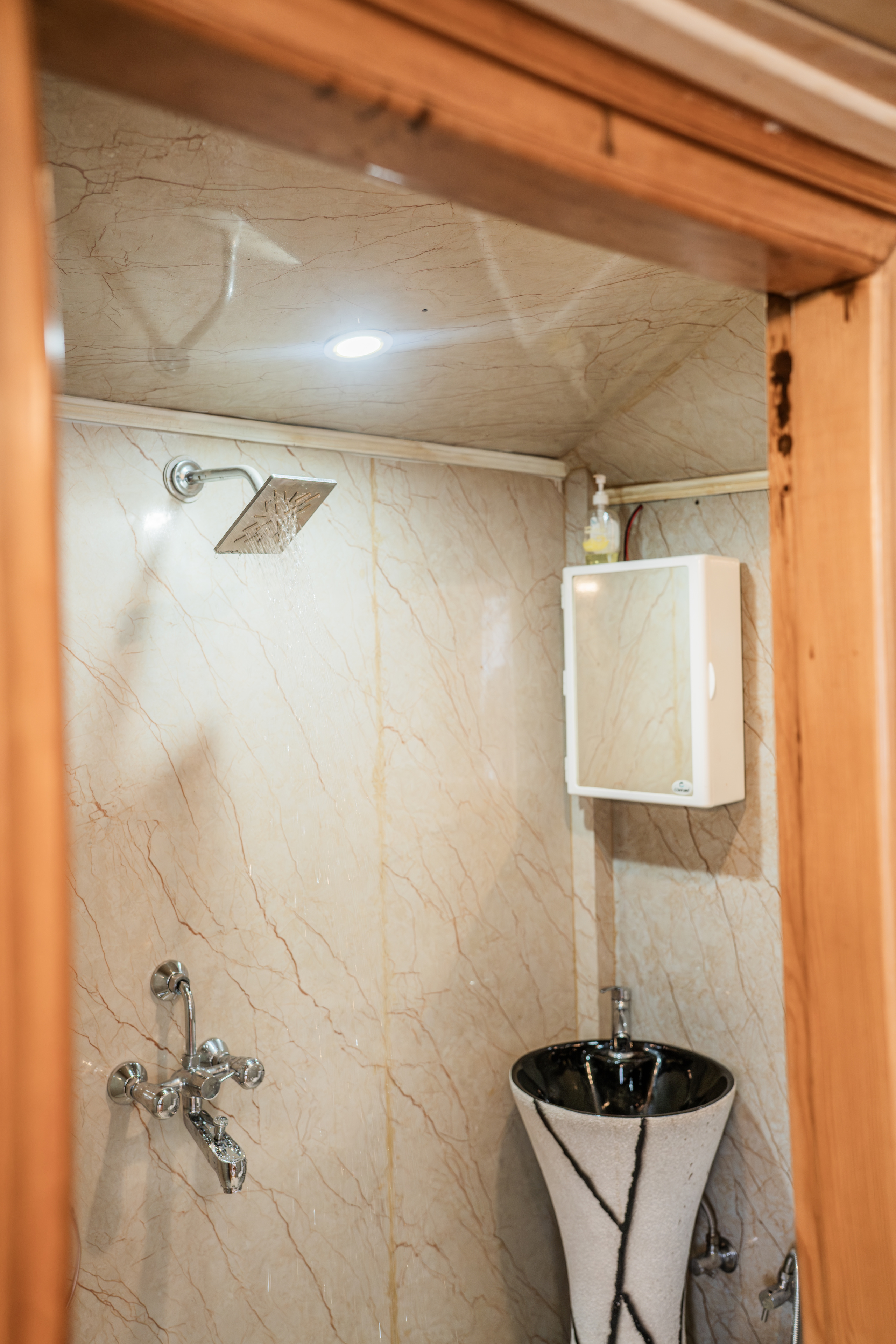 Marble-lined shower area with rain shower head and a slim wash basin